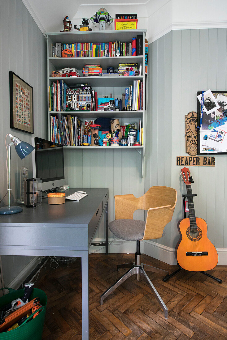 Desk and chair with bookcase and guitar in boy's room of Guildford home Surrey UK
