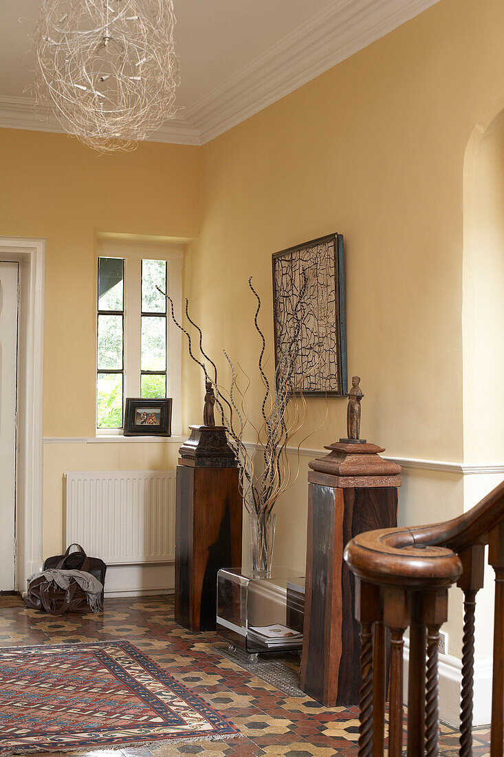 Uncurtained window and sculptures on plinths in hallway with original tiling