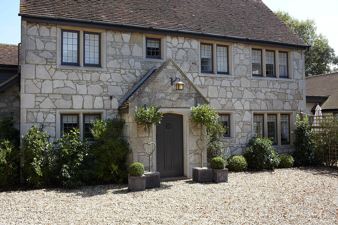 Stone facade of detached house with gravel driveway and pot plants in Brook, Isle of Wight, UK