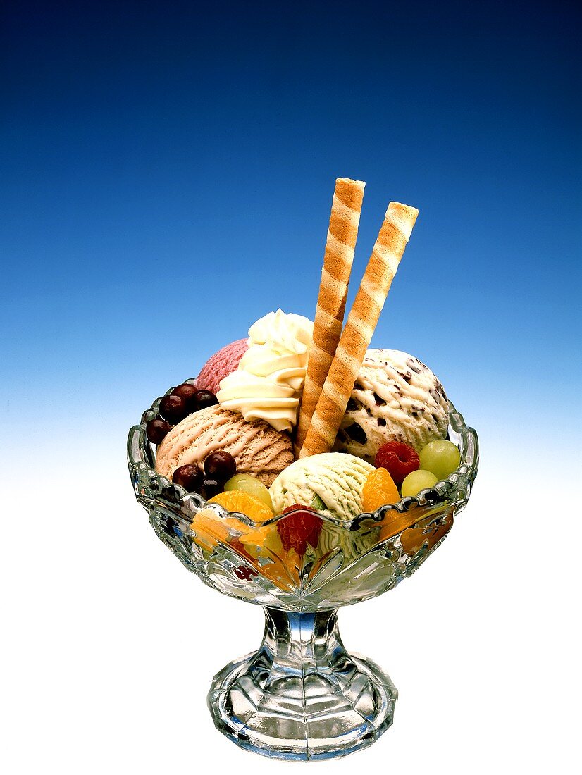 Ice cream sundae with fruit, cream and rolled wafers