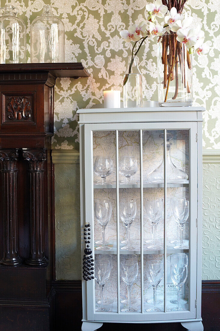 Glass fronted storage cabinet and carved wooden fireplace in Scottish apartment building UK