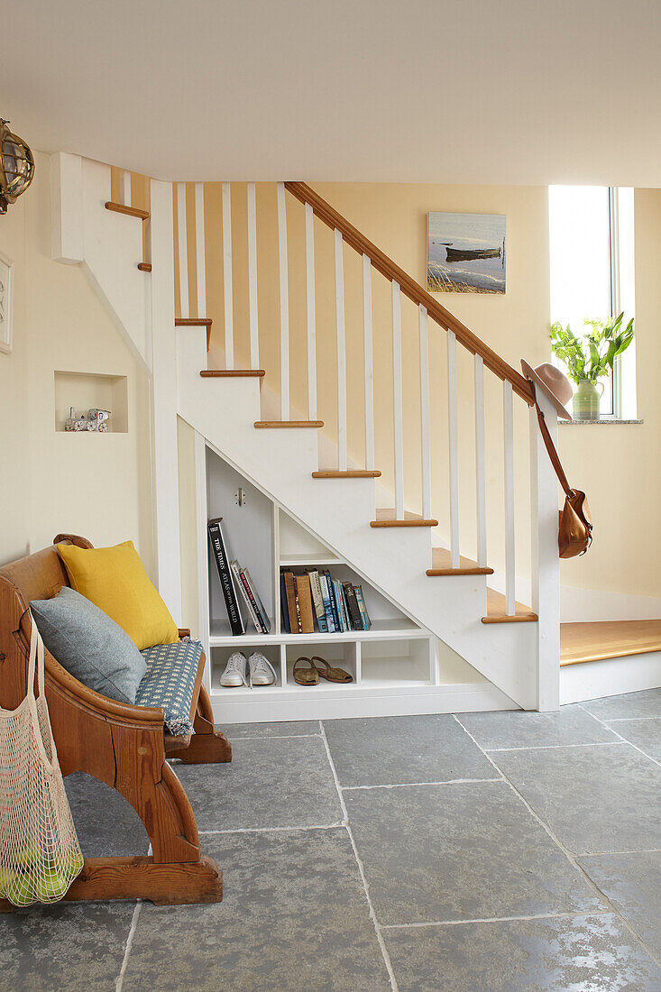 Spacious entrance hallway storage shelves under oak staircase Isle of Wight, UK