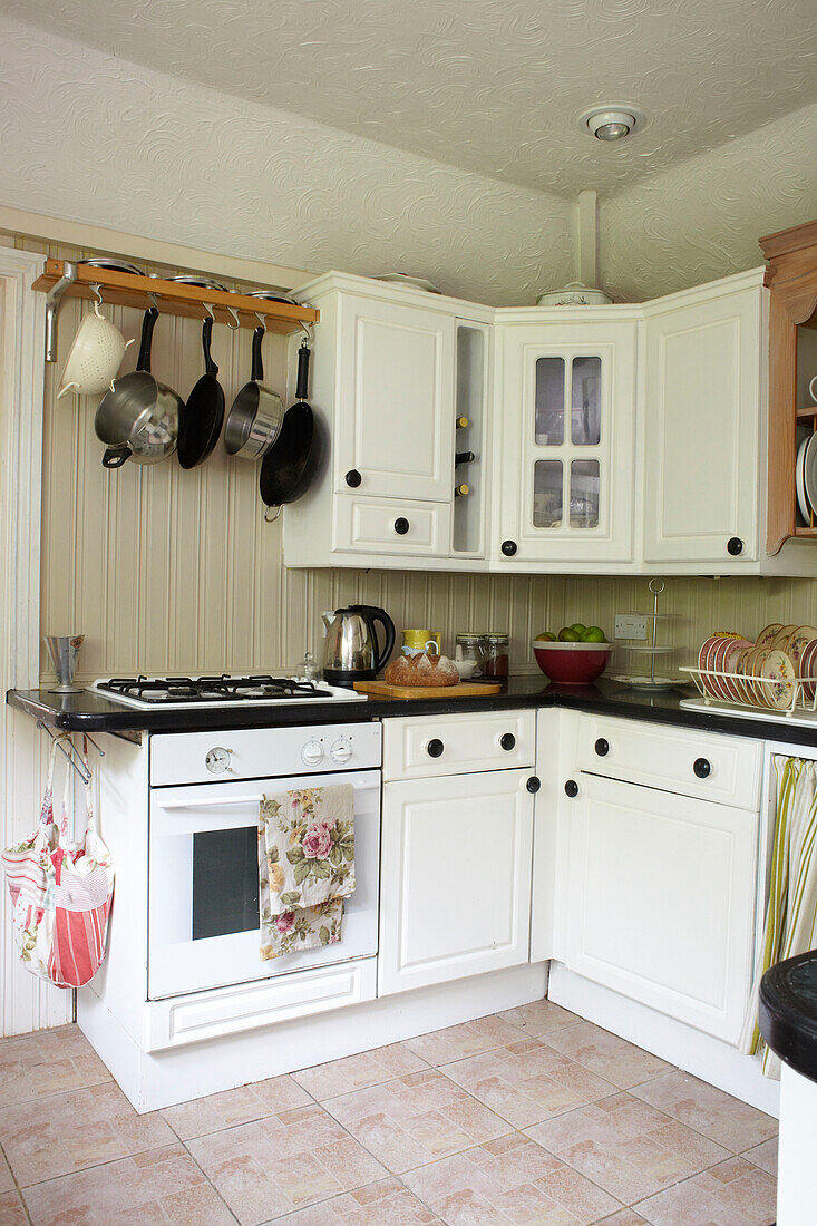 Töpfe hängen über dem Gasherd in der weißen Einbauküche eines Hauses in East Cowes, Isle of Wight, Großbritannien