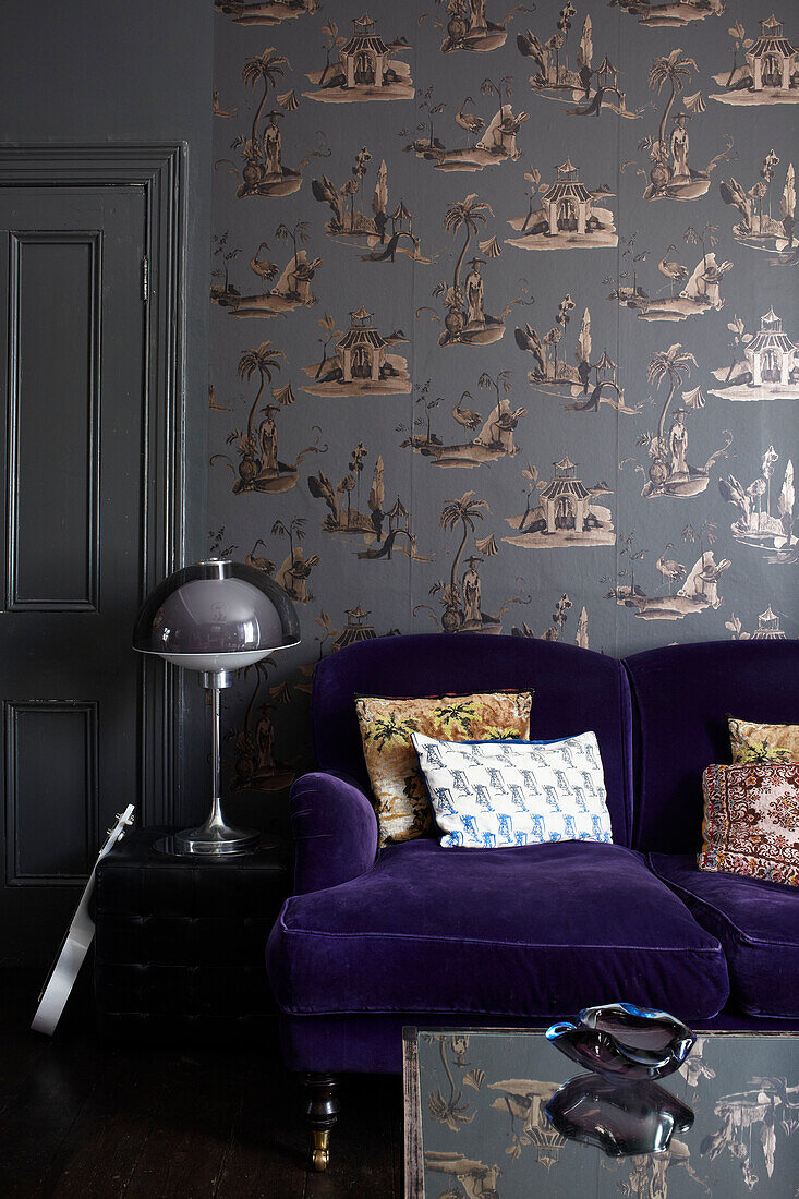 Vintage lamp with purple sofa with patterned wallpaper in retro-styled London living room, England, UK