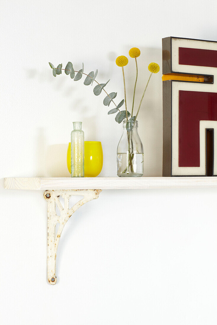 Cut flowers in bottle on bathroom shelf in London home, England, UK