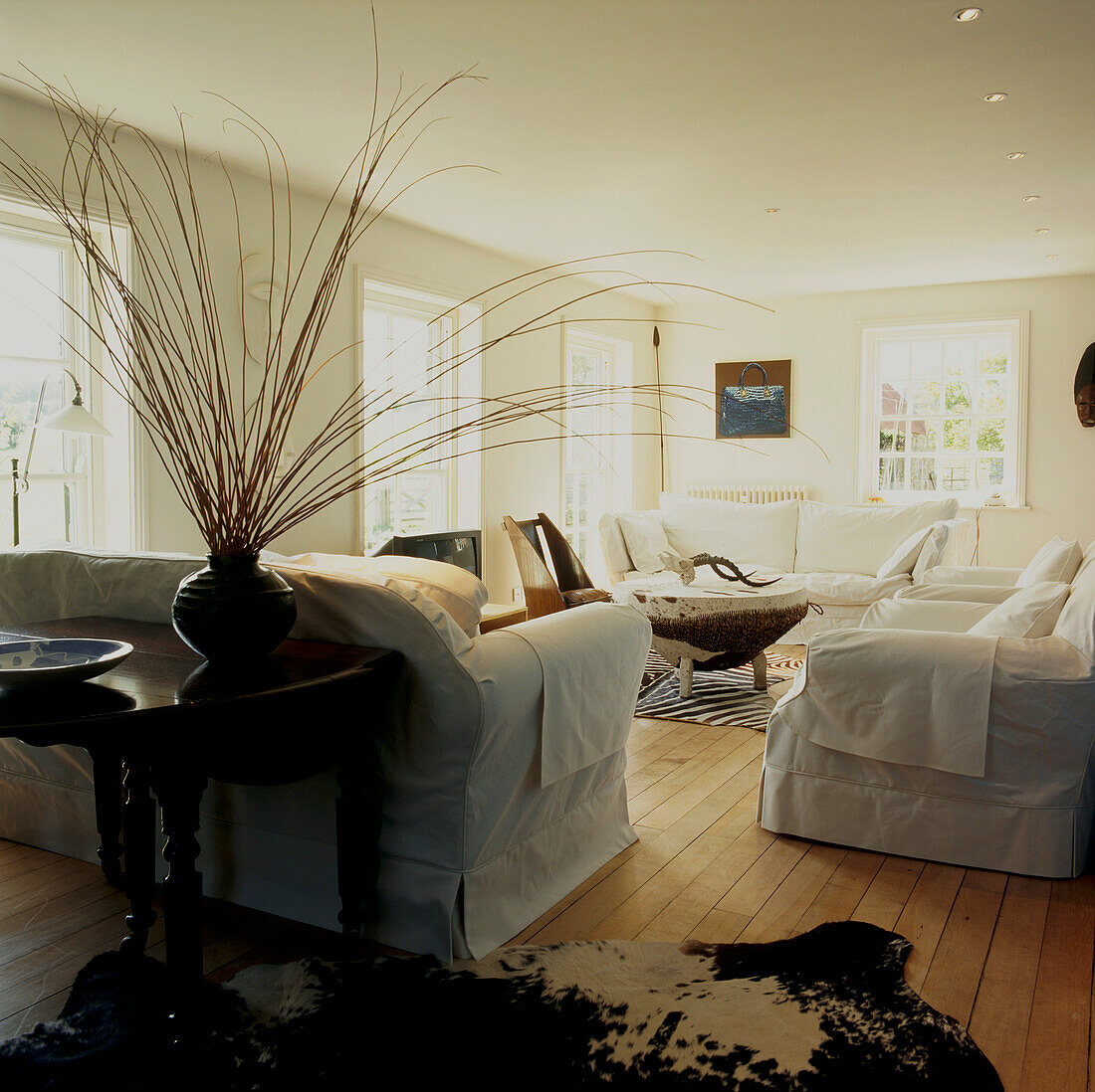 Weißes, geräumiges Wohnzimmer mit Holzdielenboden und Tierfellteppichen