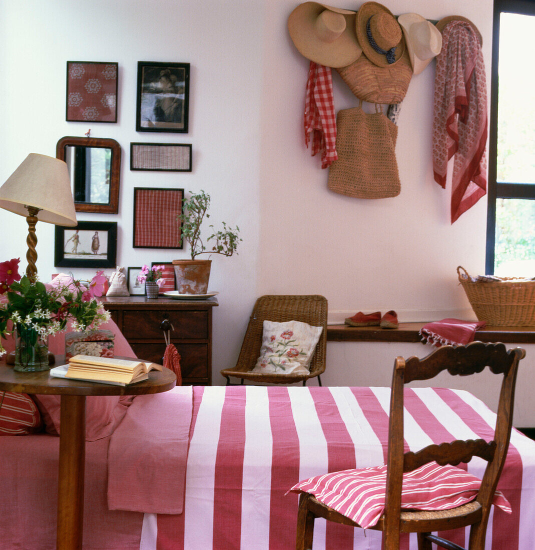 Country style pink and white bedroom with straw hats hanging on the wall