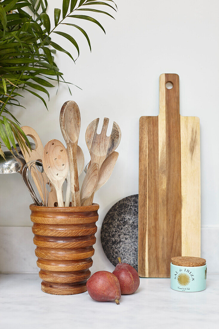 Wooden spoons and chopping board with pears in London kitchen UK