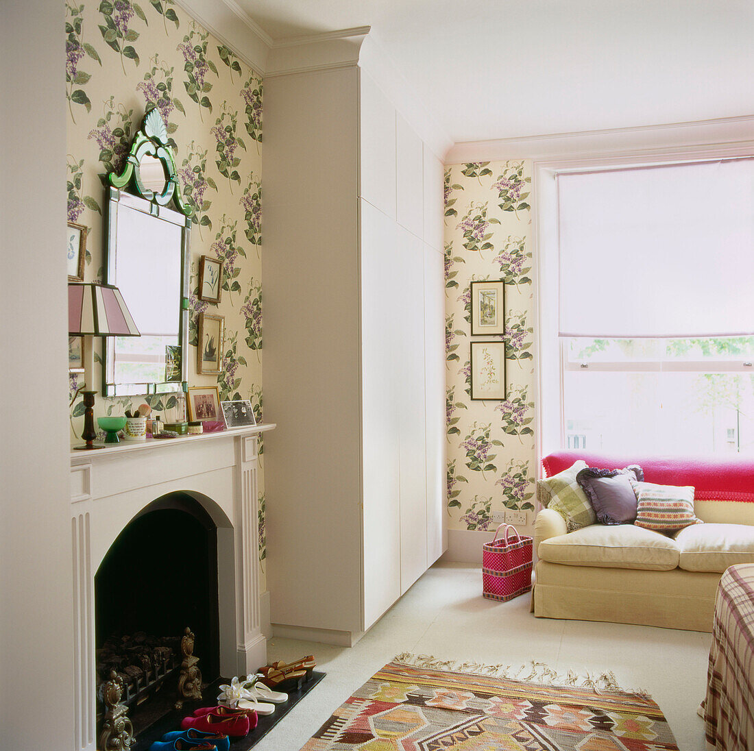Fireplace in bedroom with Venetian mirror pretty floral patterned wallpaper and built in wardrobe