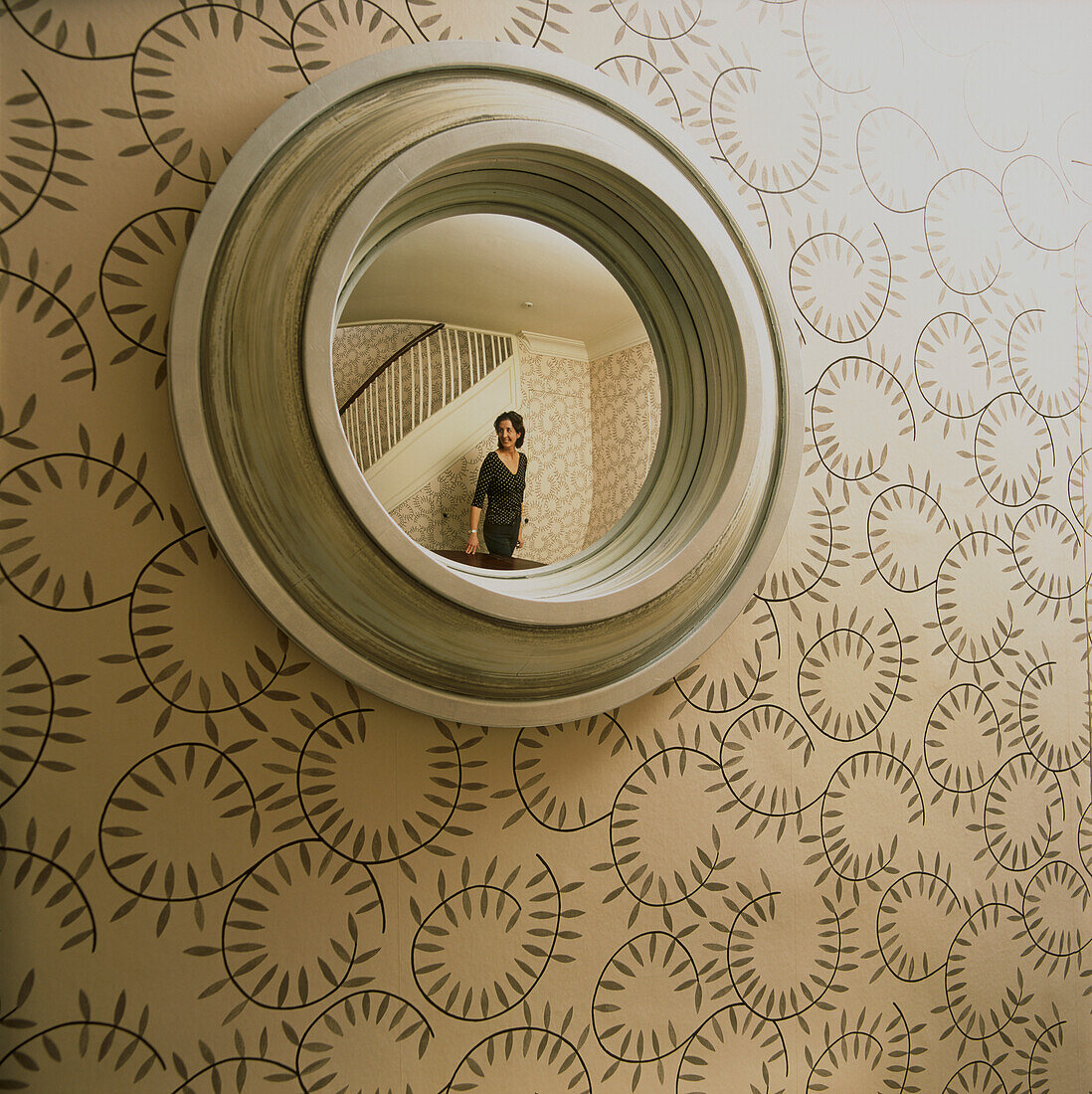 Mirror reflecting wallpapered hallway