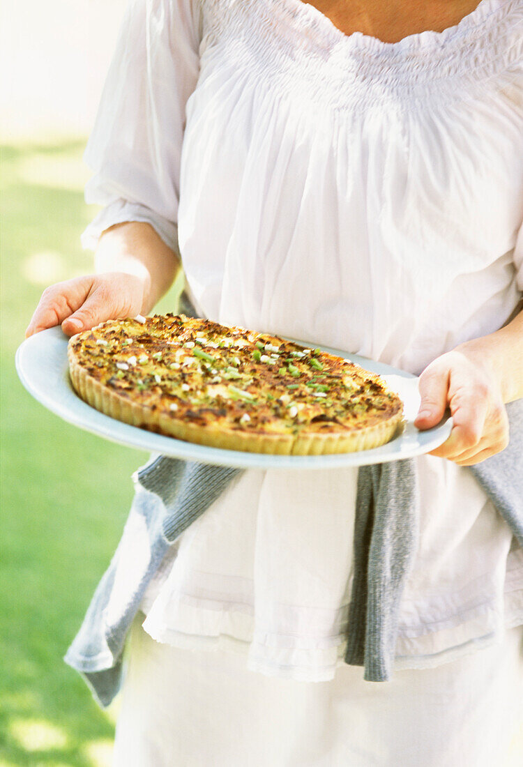 Freshly baked quiche being carried out to the garden table