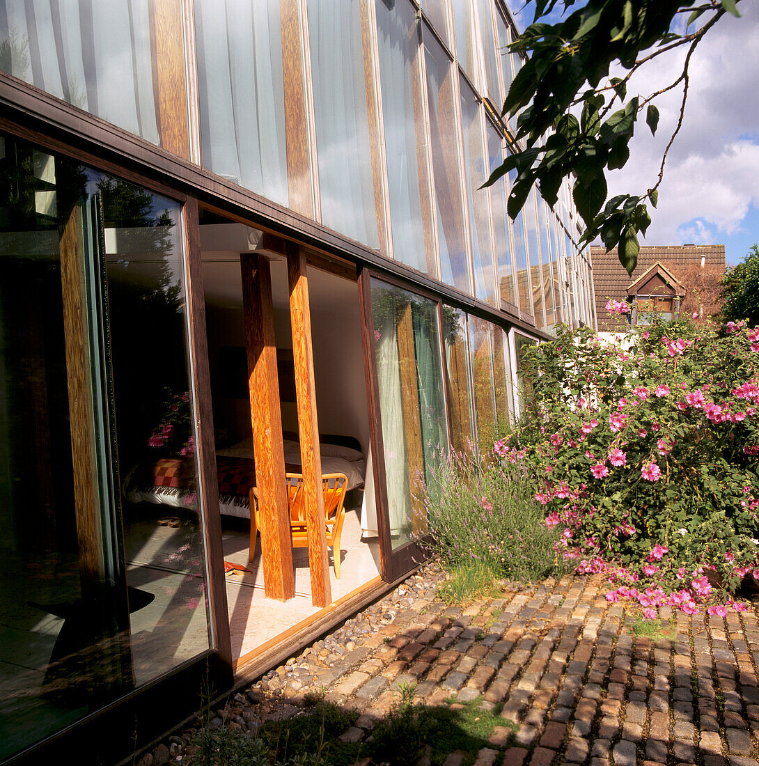 The main bedroom leading to the garden through sliding doors set in a seven degree sloping glass wall 