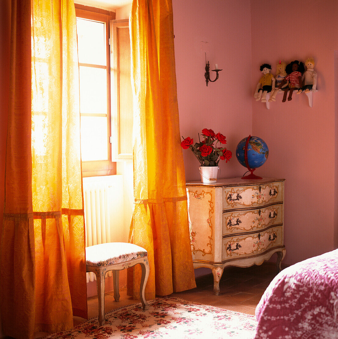 Children's bedroom detail in soft pink tones and gold full length curtains and antique Italian baroque polychrome furniture