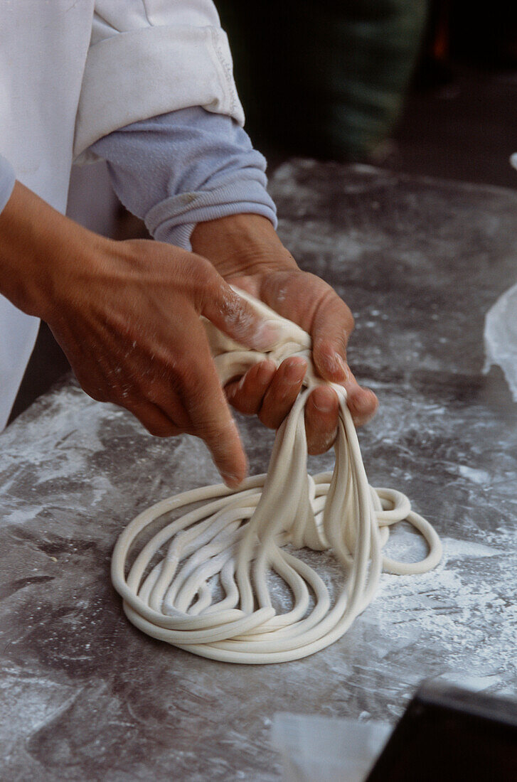 Chinese man preparing noodles in a street market in Shanghai China