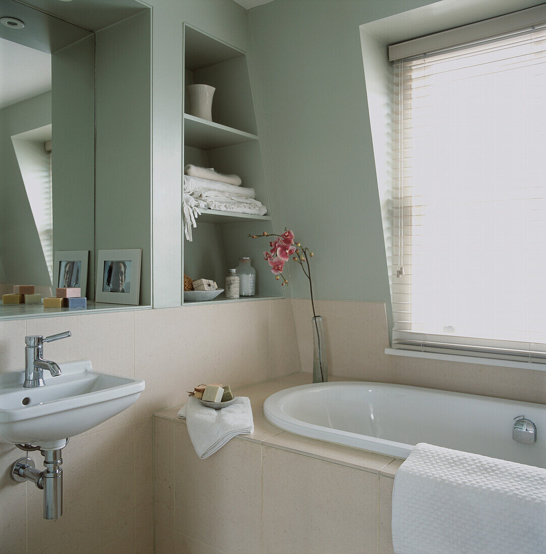 Bath set in limestone next to window in en suite attic bathroom