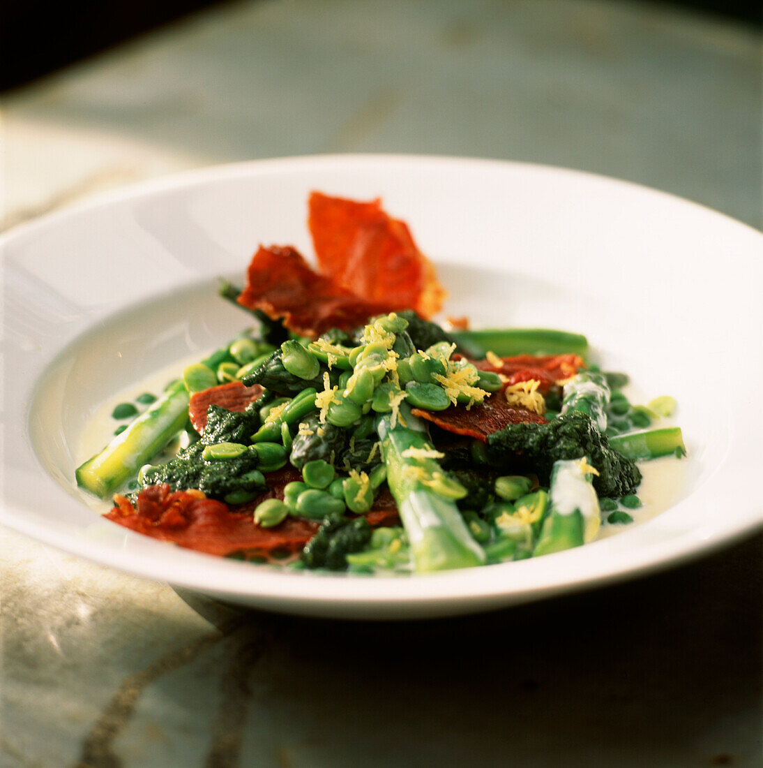 Plated asparagus and broad bean with palma ham and creme fraiche