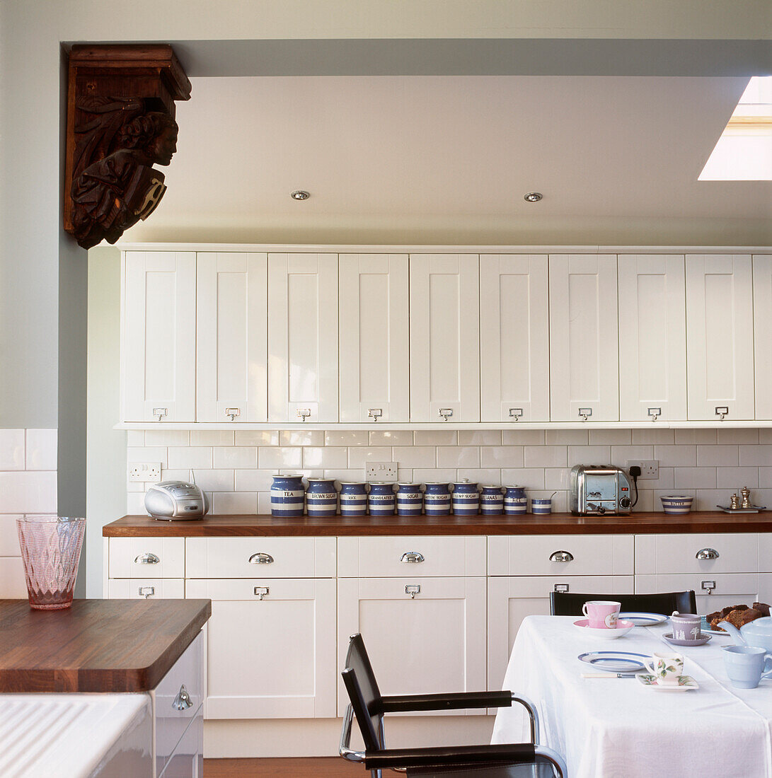 Weiße Küchenschränke, Frühstückstisch und Arbeitsplatten aus Holz