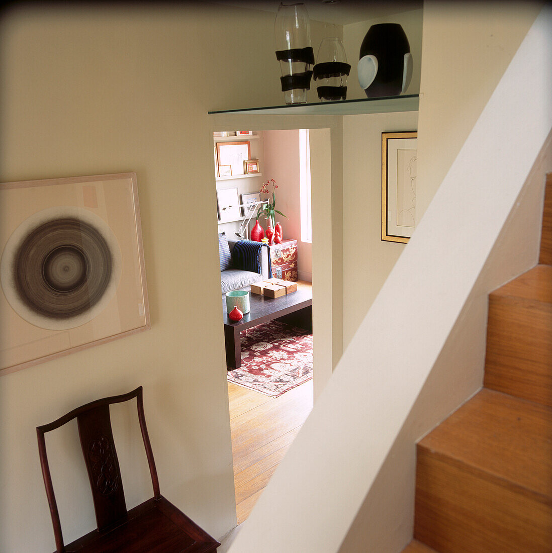 Looking down the stairs to the living room with glass vases displayed on a high level shelf