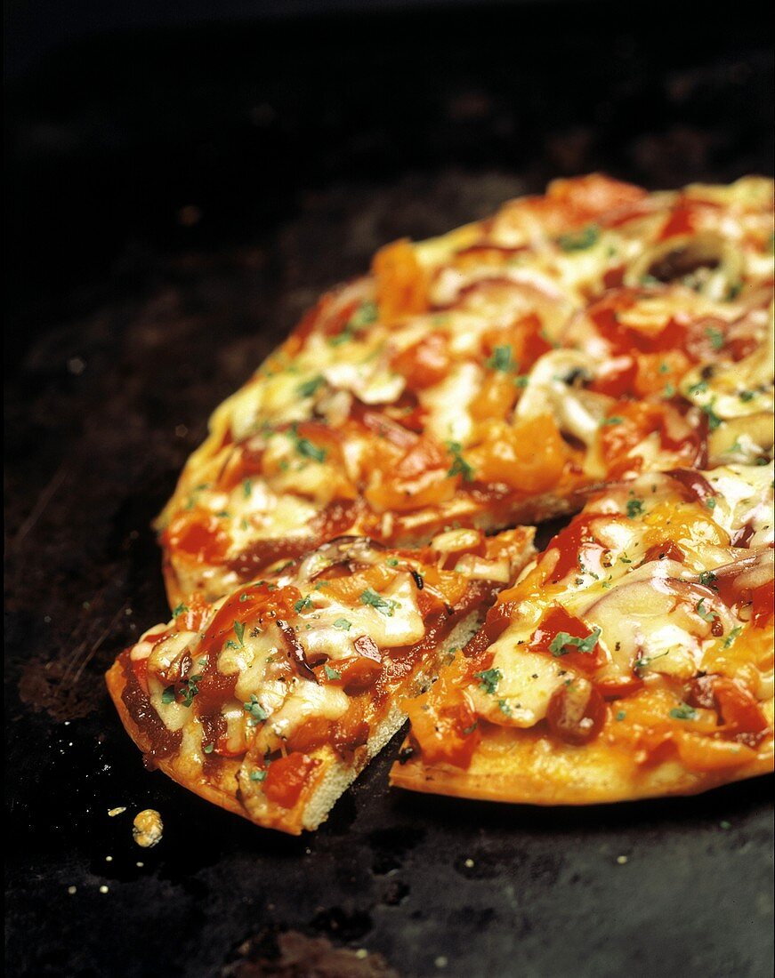 Pizza mit Tomaten, Paprika, Schinken & Käse, angeschnitten