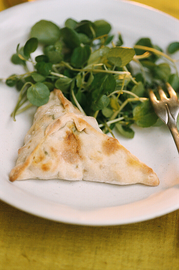 White plate with a pumpkin fatayer and watercress 