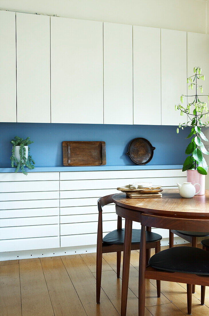 Open plan contemporary kitchen dining room with fitted cupboards and a Danish style dining table and chairs