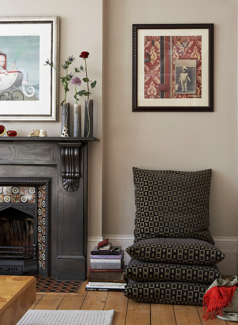 Floor cushions and single stem flowers at Victorian fireside in in London townhouse, UK