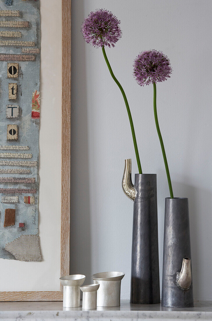 Single stem flowers in vases on mantlepiece in London townhouse, UK