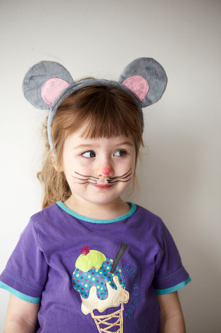 Little girl with purple T-shirt dressing up in a mouse mask