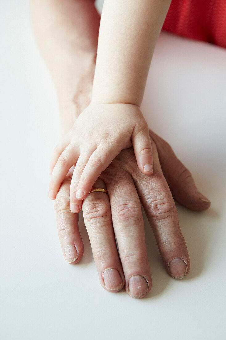 Three year old hand on mature adults hand