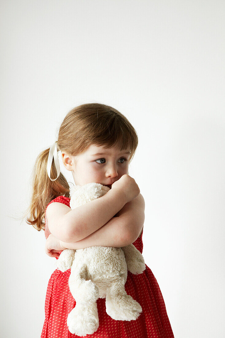 Young girl in red dress holding a teddybear