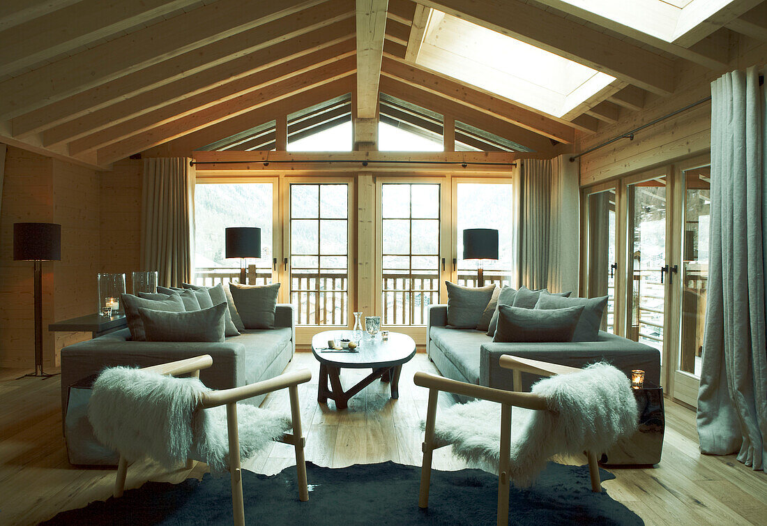 Passende Sofas und Sessel mit Couchtisch in einem Wohnzimmer mit Balken in einem luxuriösen Chalet in Zermatt, Schweiz