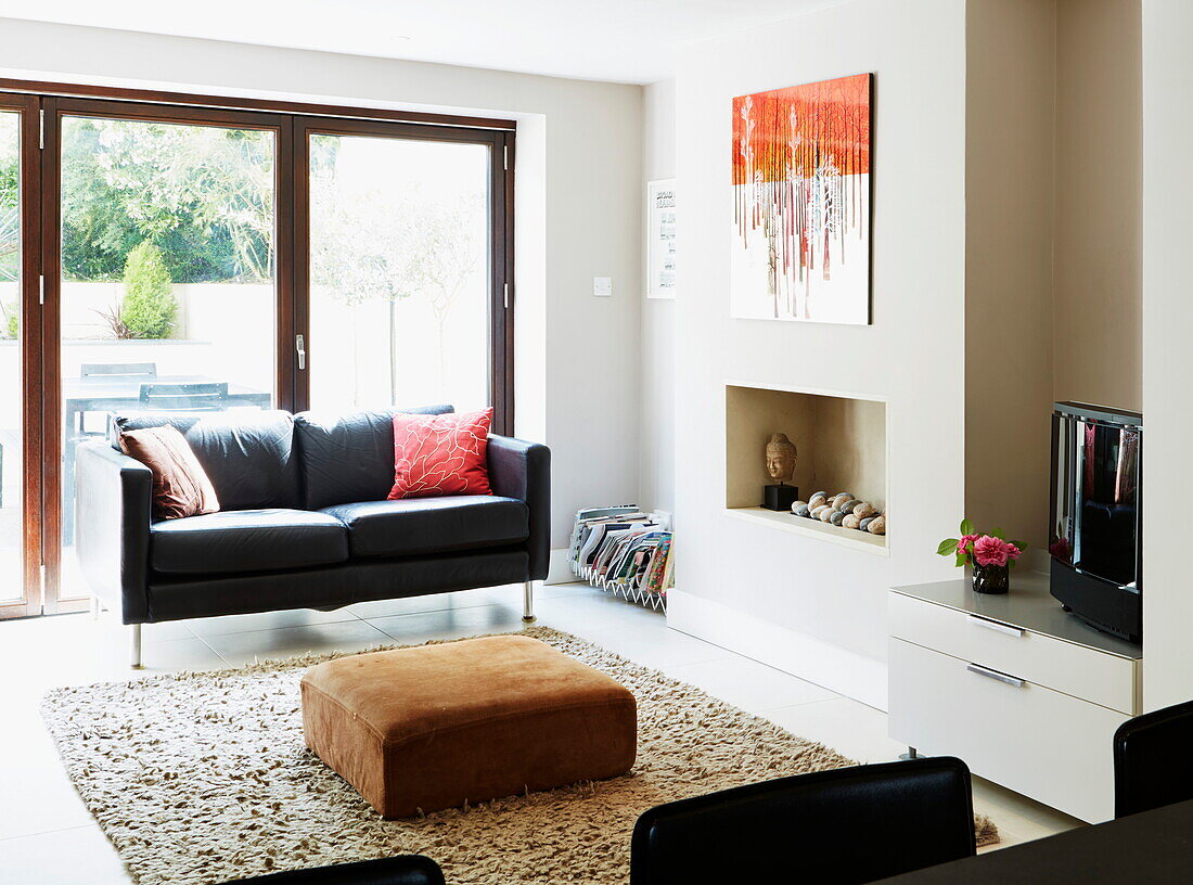 Black leather two-seater sofa in living room of London townhouse, England, UK