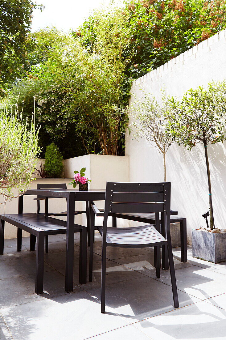 Bench seat and chairs at garden table of London townhouse, England, UK