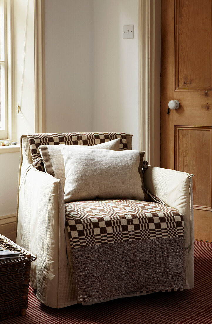 Comfy armchair in corner of living room with patterned blanket