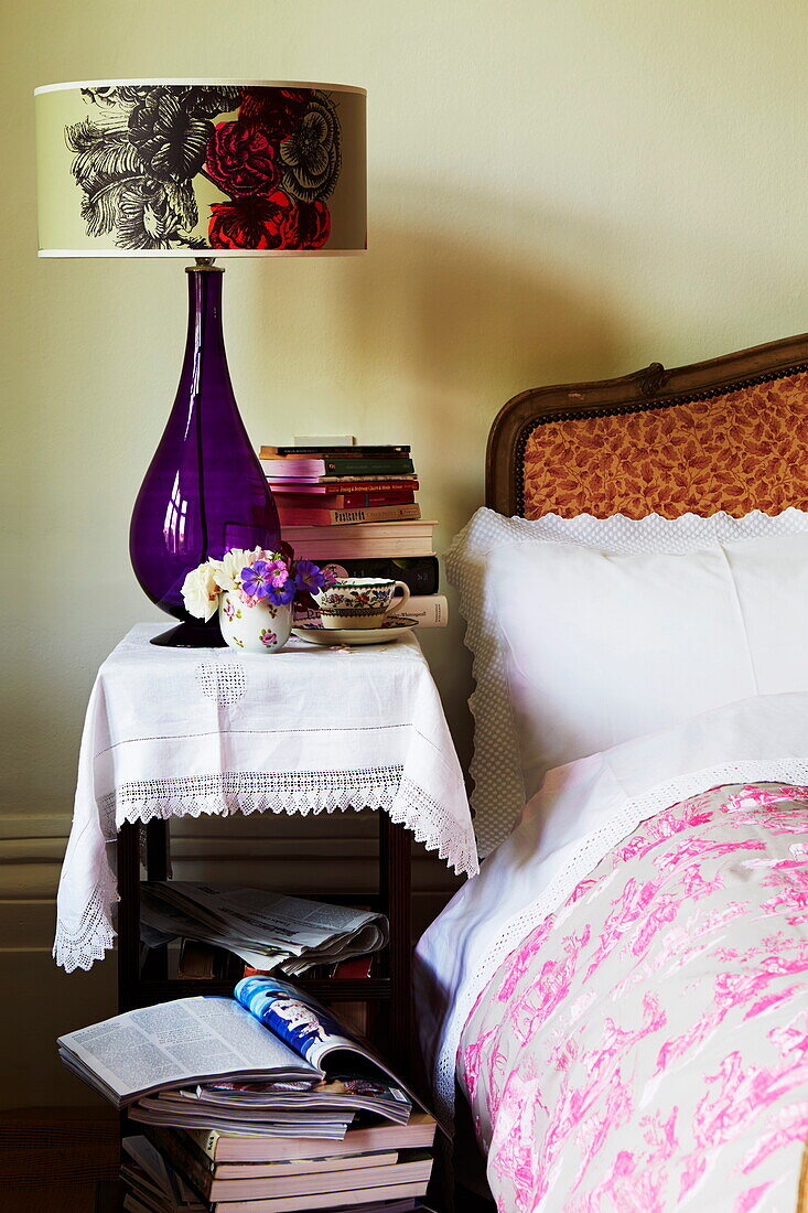 Purple lamp on bedside table with books in old London townhouse, England, UK