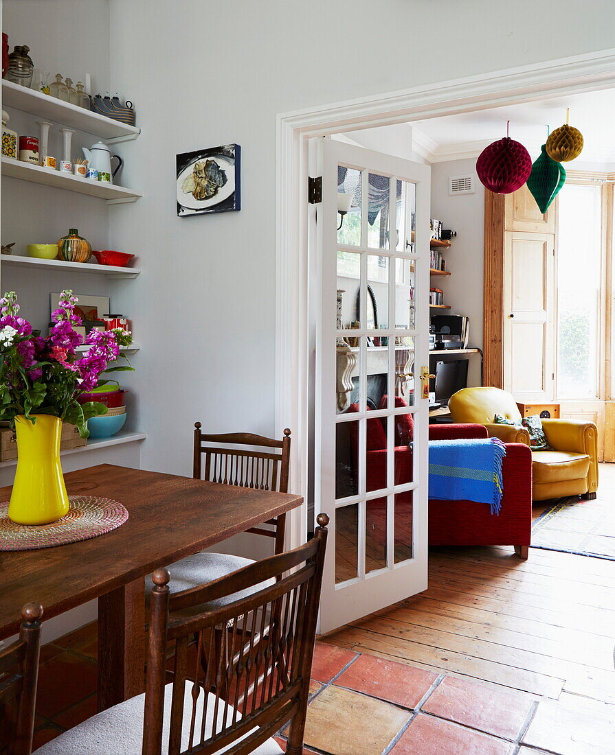 Esstisch aus Holz mit Blick durch die Tür zum Wohnzimmer in einem Haus in London, England, UK