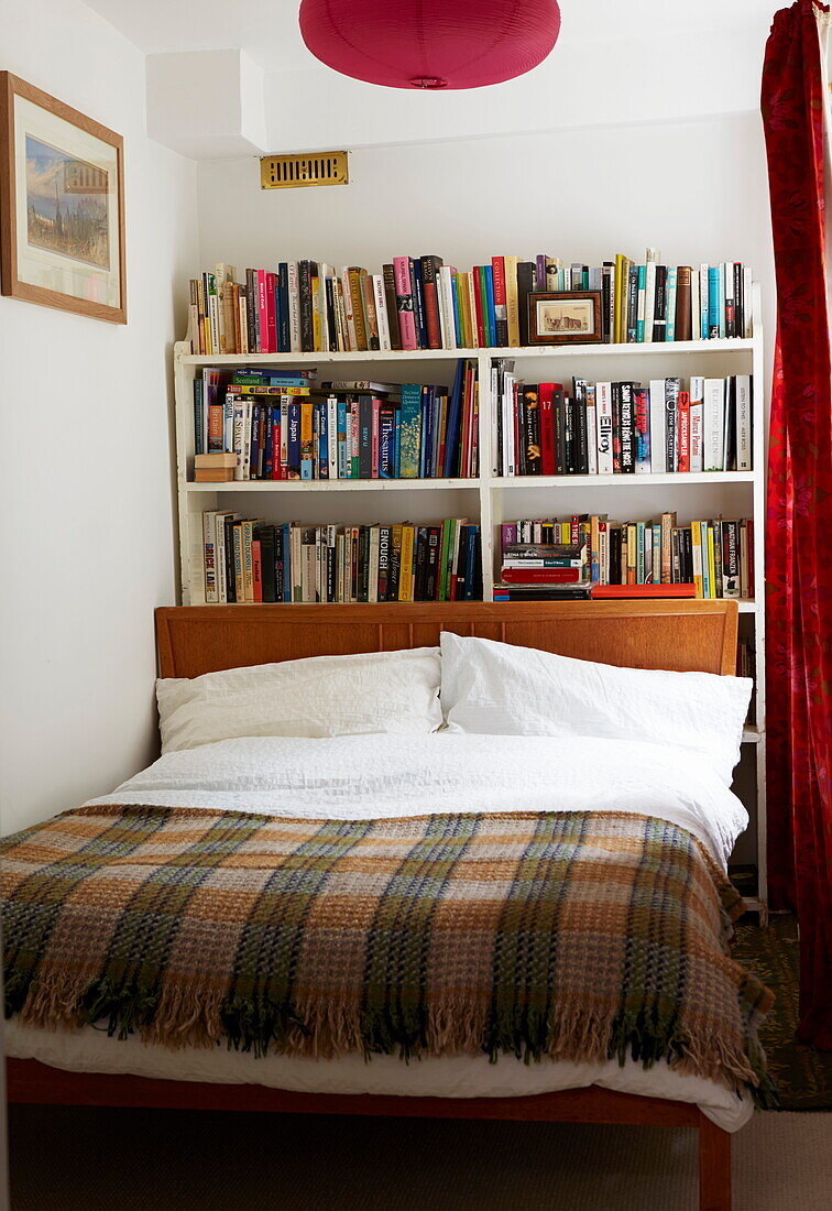 Karierte Decke auf einem Doppelbett mit Büchern in einem Haus in London, England, UK