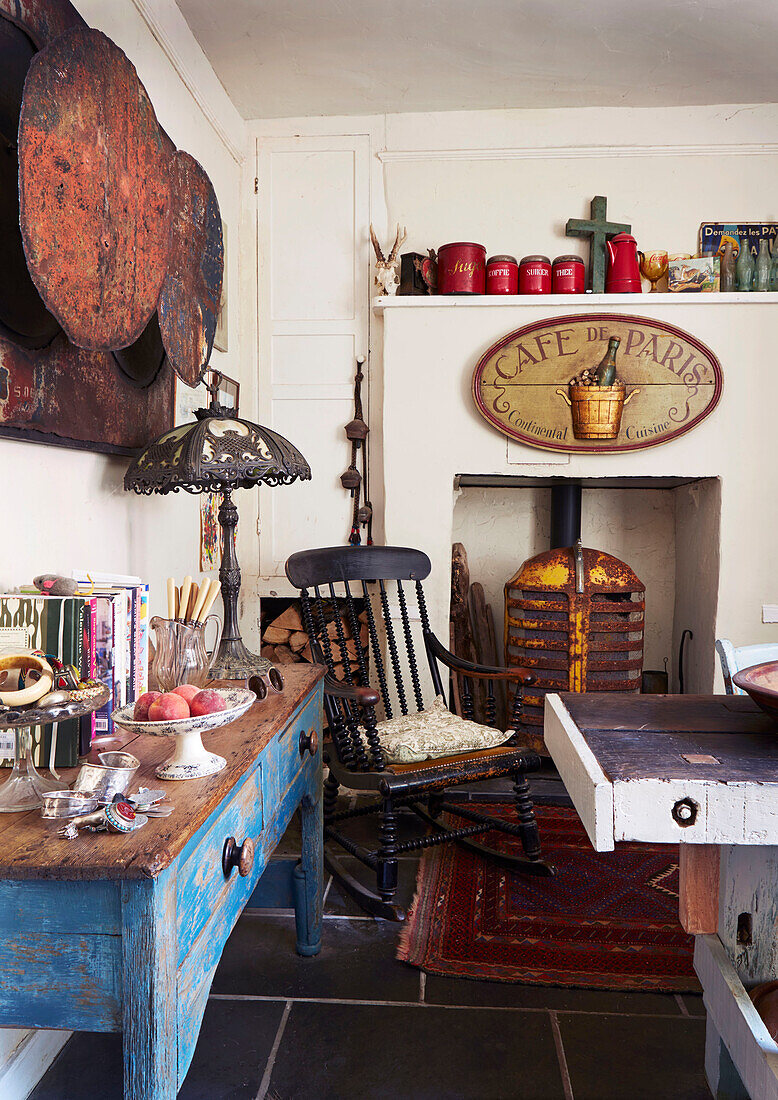 Vintage metal sign and rocking chair at fireplace in Evershot kitchen, Dorset, Kent, UK