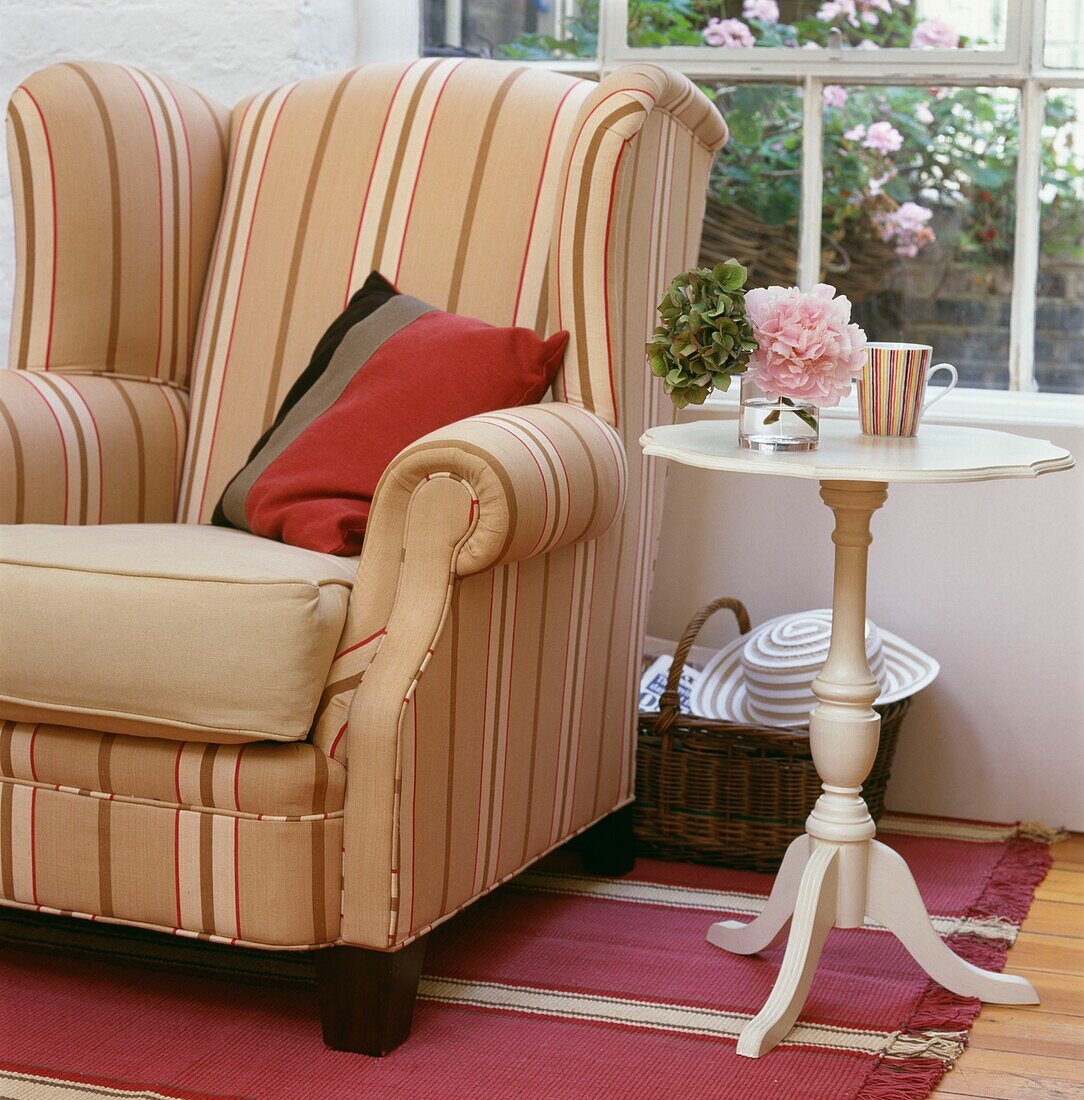 Gestreifter Sessel und Beistelltisch mit Sockel vor einem Fenster