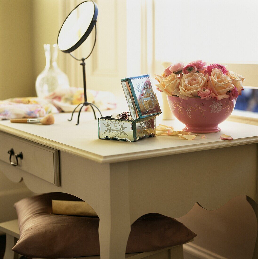 Circular freestanding mirror on painted dressing table with roses