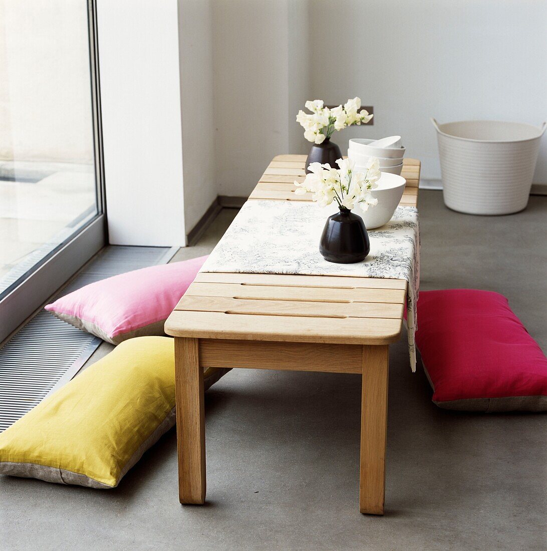 Bowls and cut flowers on low table with floor cushions