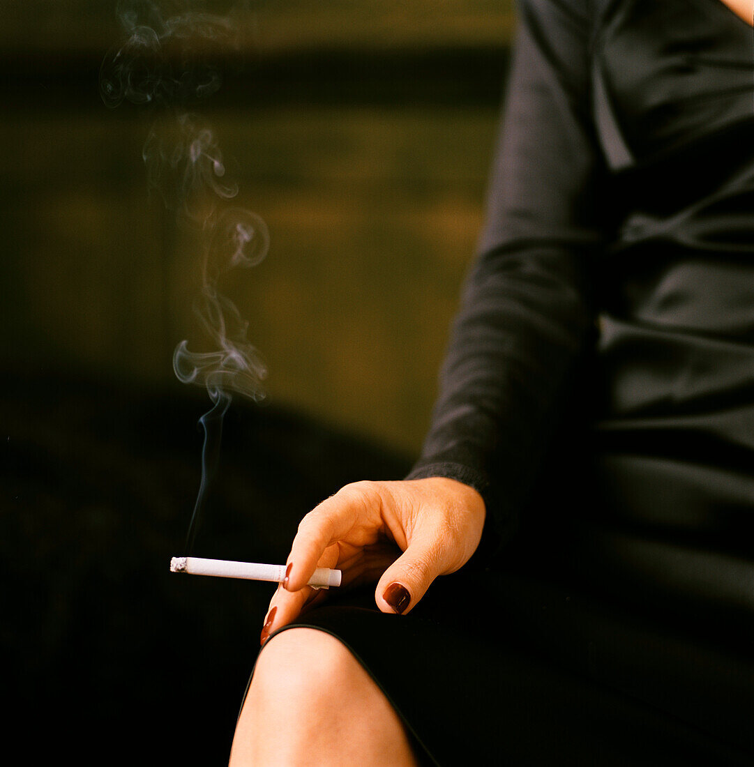 Frau raucht eine Zigarette in einer Bar