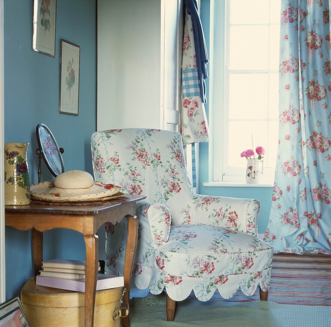 Floral patterned armchair with side table in corner of room at window 
