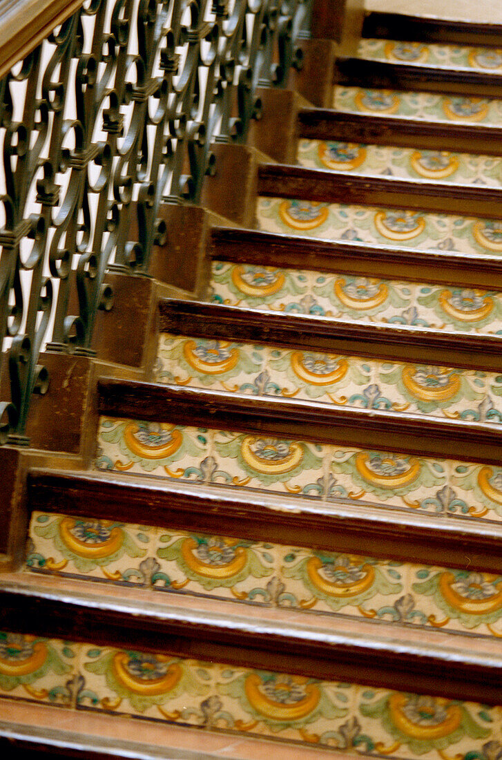 Decorative tile steps on an ornate ironwork staircase inside the National Museum of Ceramics in Valencia