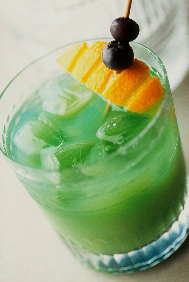 Harakiri Cocktail made with Midori Melon Liqueur white rum and lemon juice garnished with orange and blueberries