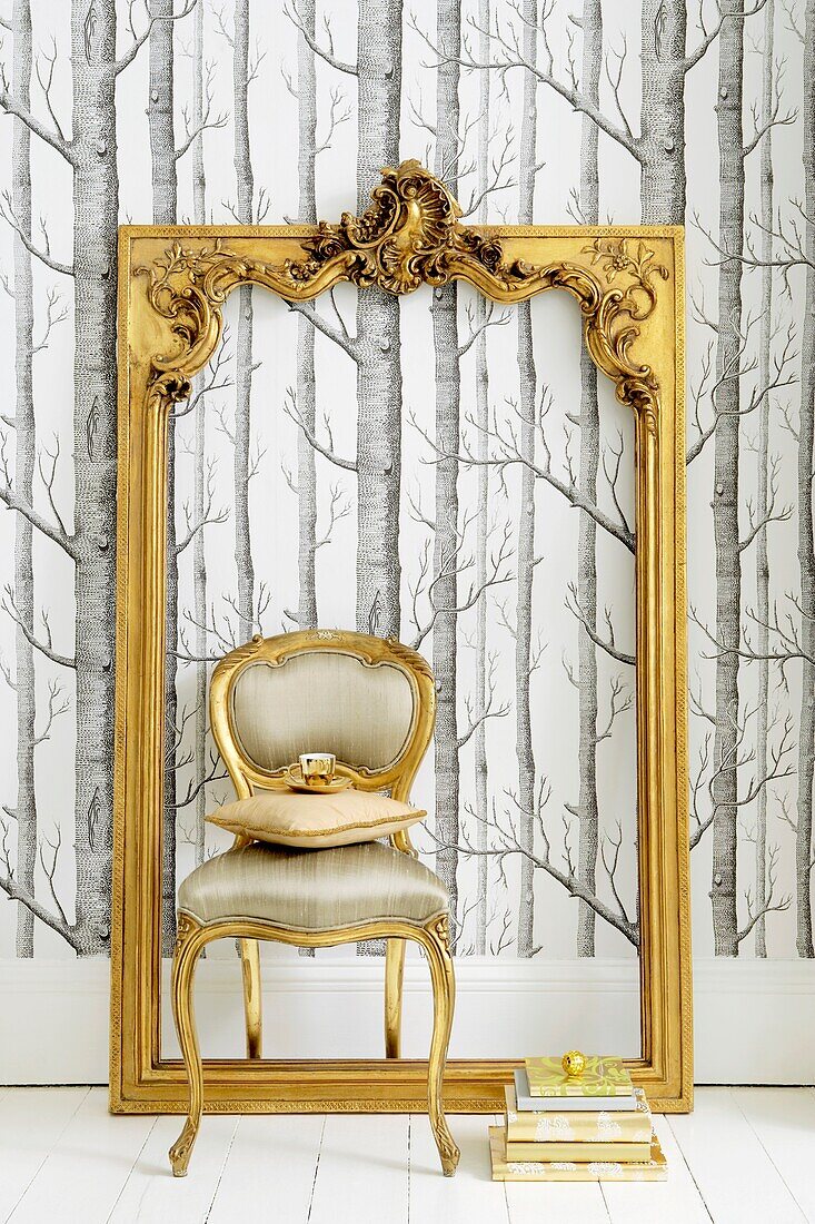 Still life with tree silhouette wallpaper and ornate gilt picture frame and upholstered 