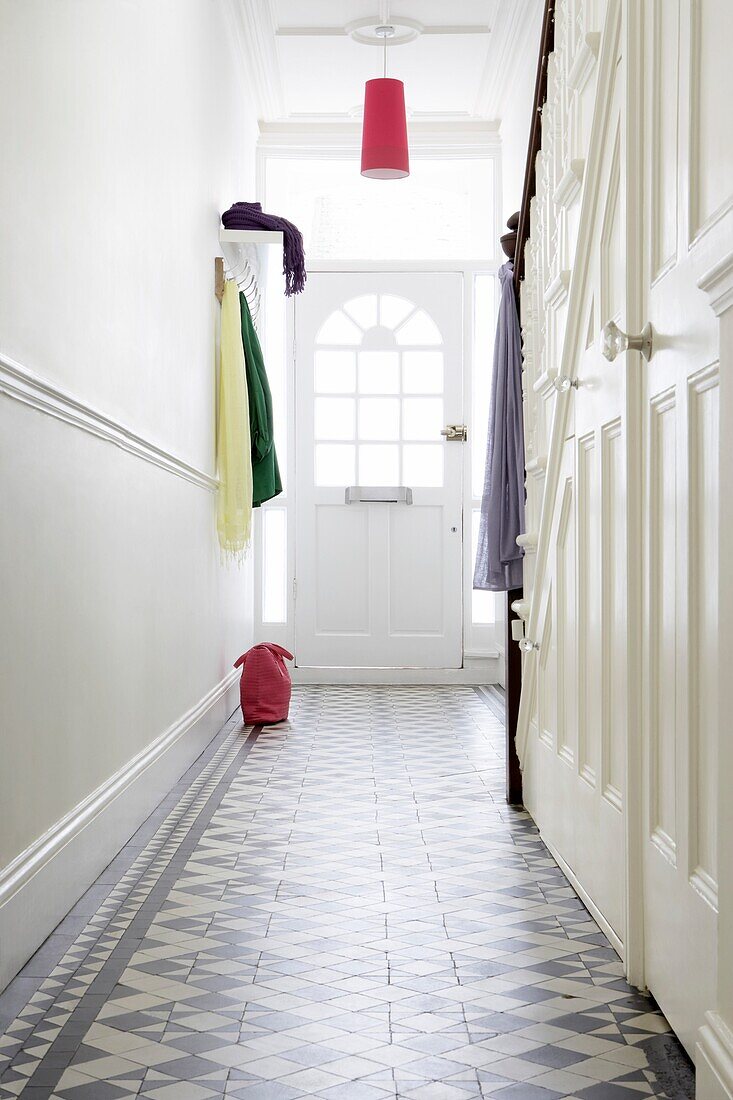 View to glass panelled door in Victorian hall with black and white geometric encaustic floor tiles