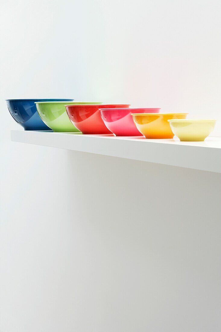 Shelf with different sized bowls with brightly coloured glazes