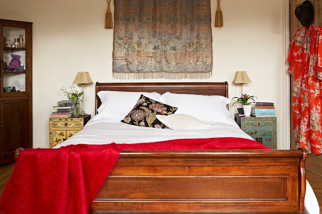 Oriental fabrics in bedroom with antique wooden bed and corner cabinet in London home   UK