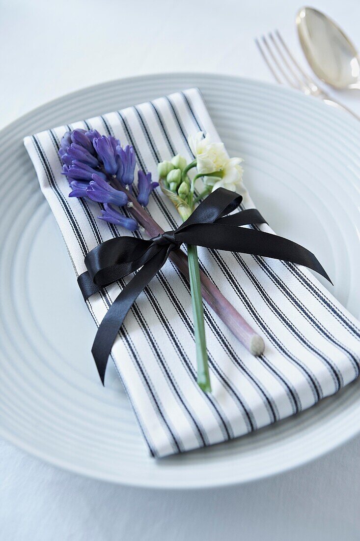 Cut flowers with striped napkin and black bow on place setting